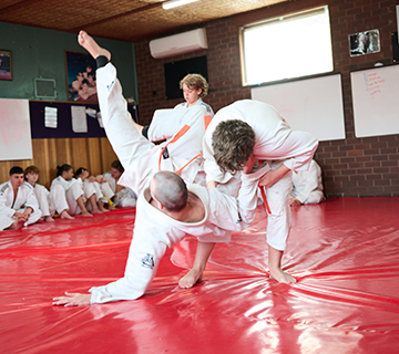 Students practising a judo throw on the mat