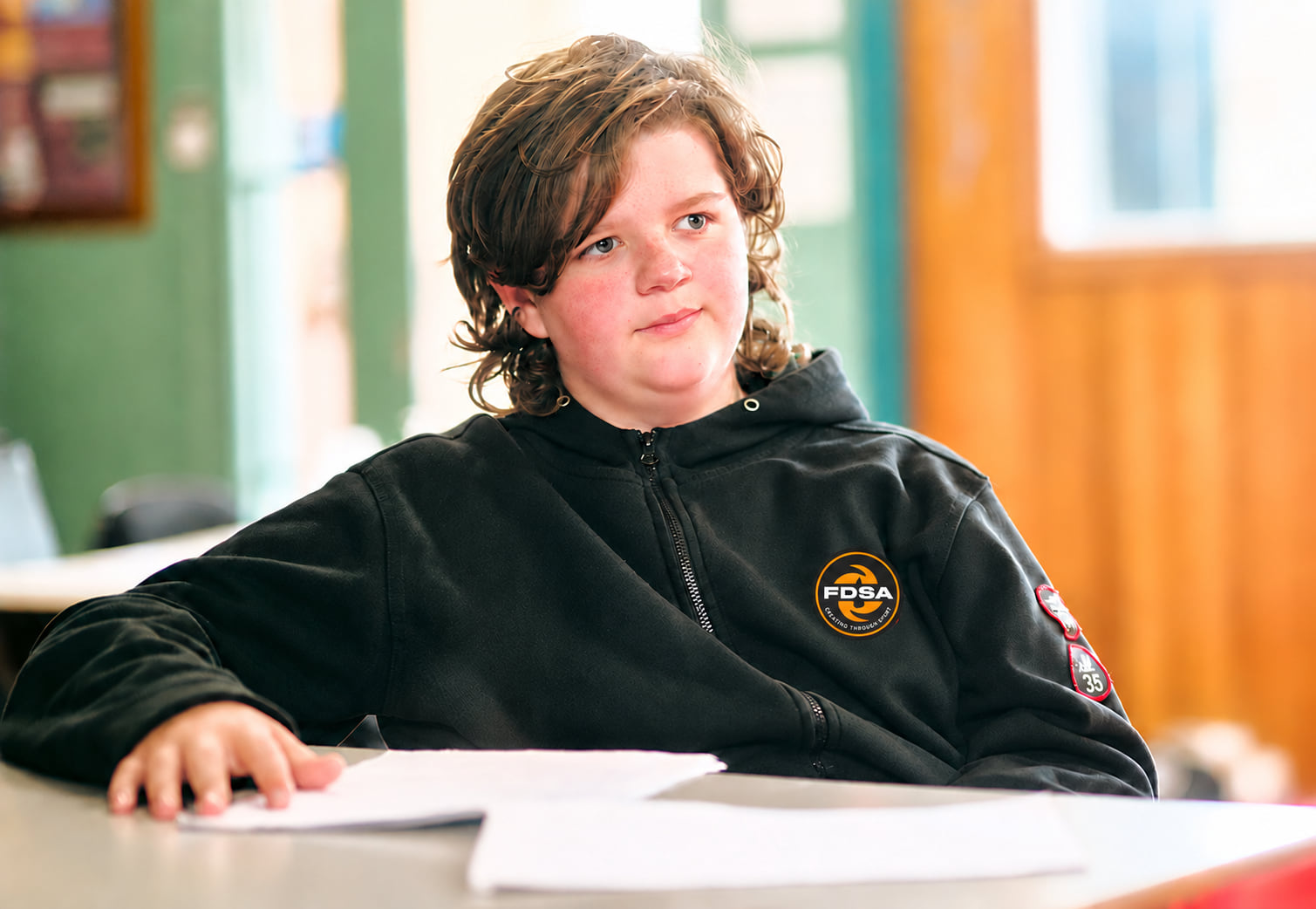 A student smiling at his desk